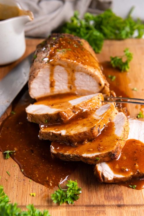 Partially sliced instant pot pork loin drizzled with gravy.