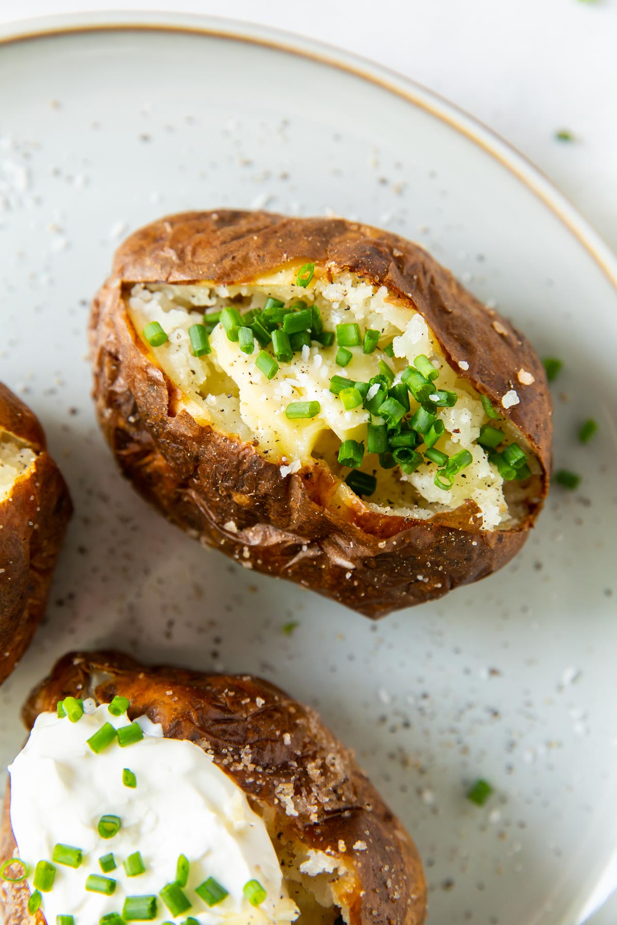 Air fryer baked potato topped with butter and chives.