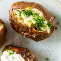 close up of air fryer baked potato topped with butter and chives