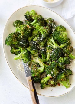 Air fryer broccoli with parmesan and red pepper flakes on a serving dish.