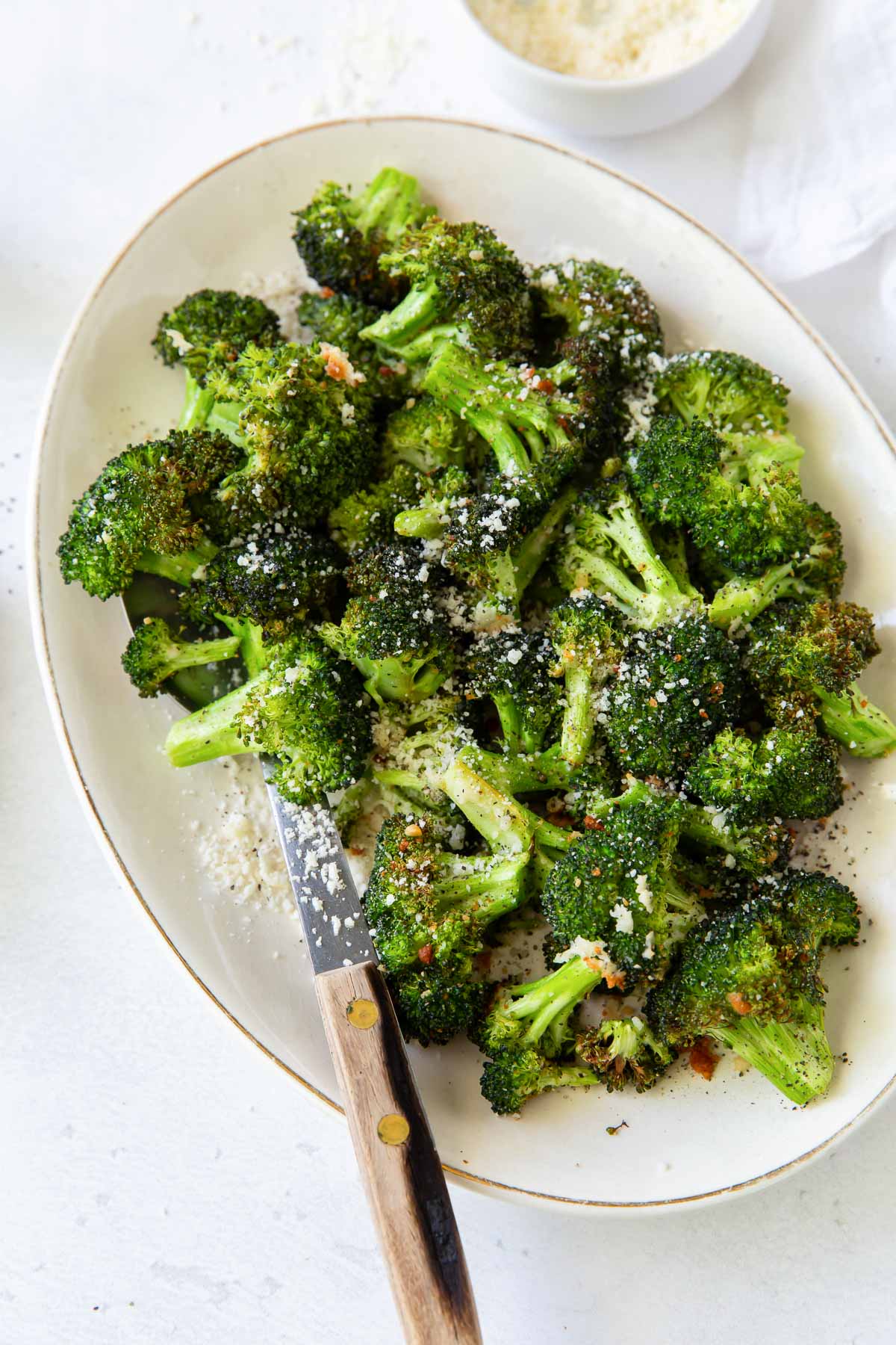 air fryer broccoli with parmesan and red pepper flakes on a serving dish