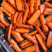 Close up of cooked carrots in air fryer basket.