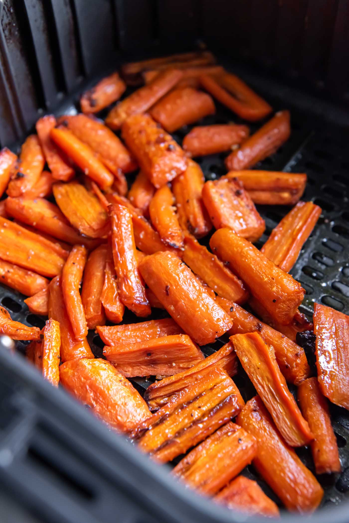 Cooked carrots in air fryer basket.