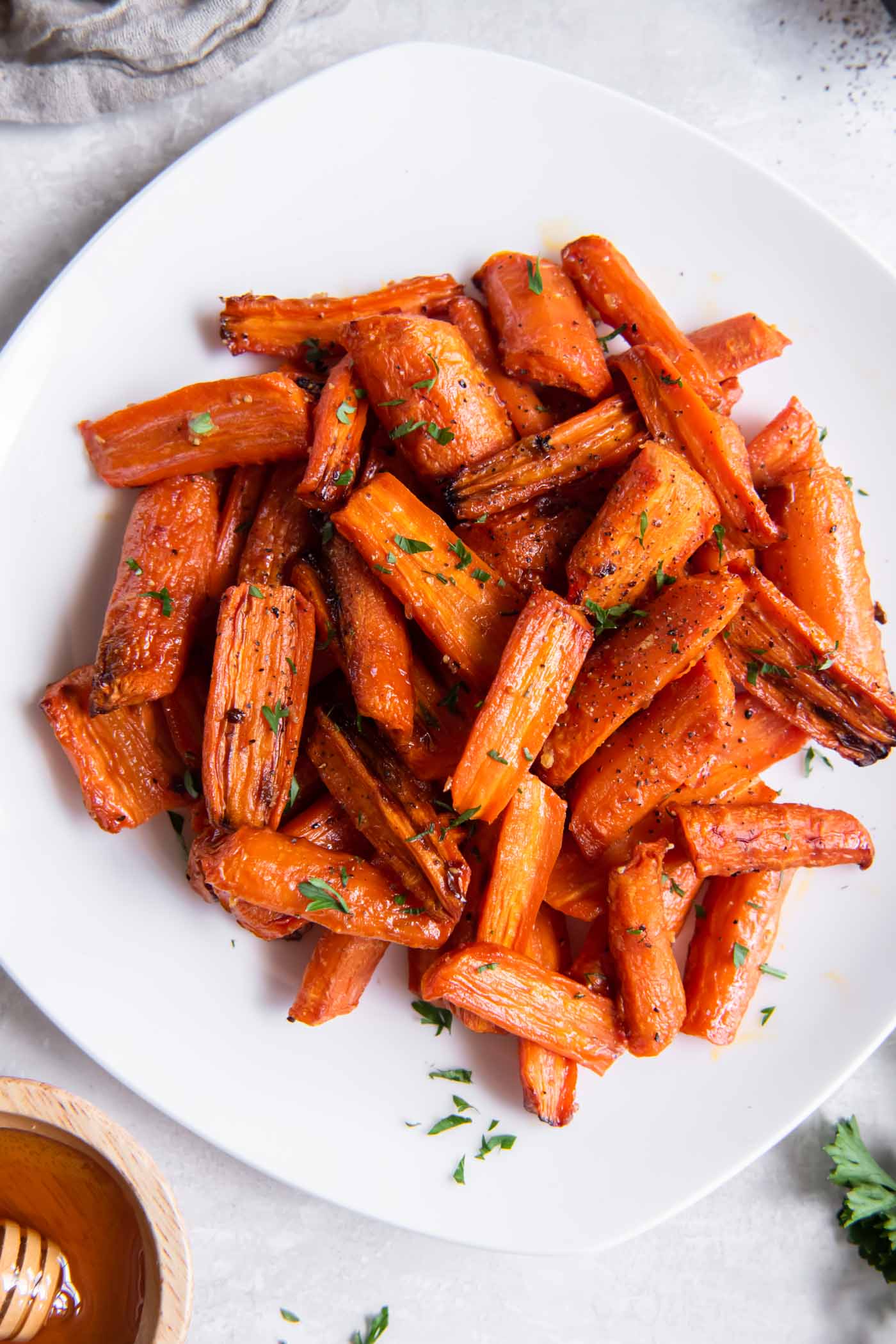 Air fryer carrots on a serving plate with fresh parsley garnish.