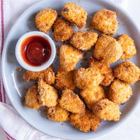Air fryer chicken nuggets on a plate with a small dish of ketchup.
