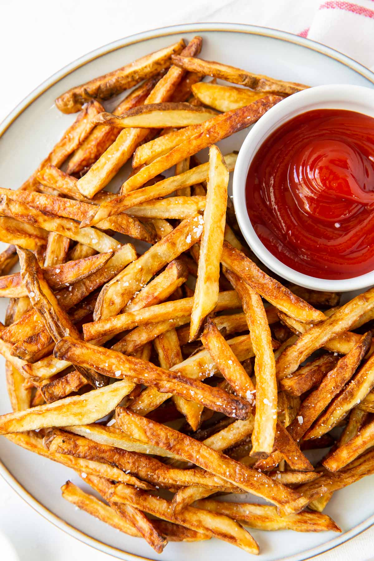 a plate of air fryer french fries with a small dish of ketchup