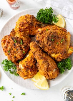 air fryer fried chicken legs and thighs on a plate garnished with parsley and lemon