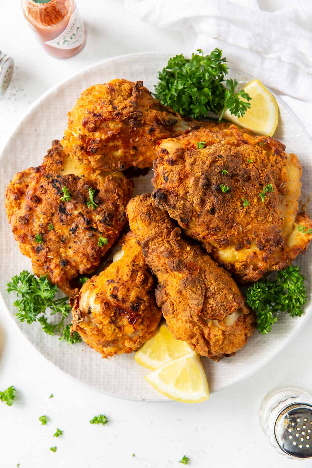 air fryer fried chicken legs and thighs on a plate garnished with parsley and lemon