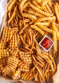 Shoestring, waffle and crinkle cut french fries served with small dish of ketchup.