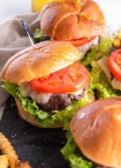 Air fryer hamburgers served on buns with cheese, lettuce and tomato.