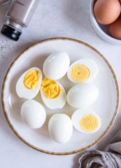 Peeled air fryer hard boiled eggs on a plate with some whole and some cut in half.