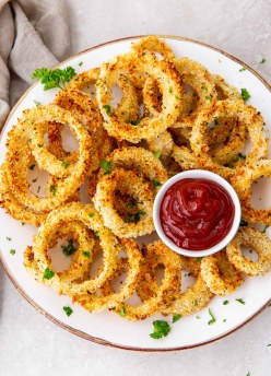 Air fryer onion rings served on a plate with ketchup.