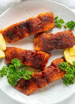 four air fried salmon fillets on a plate with parsley and lemon slices