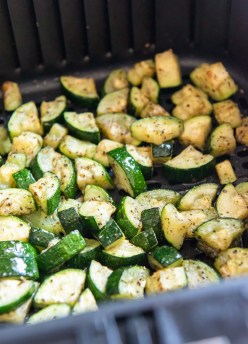 Cooked zucchini pieces in air fryer basket.