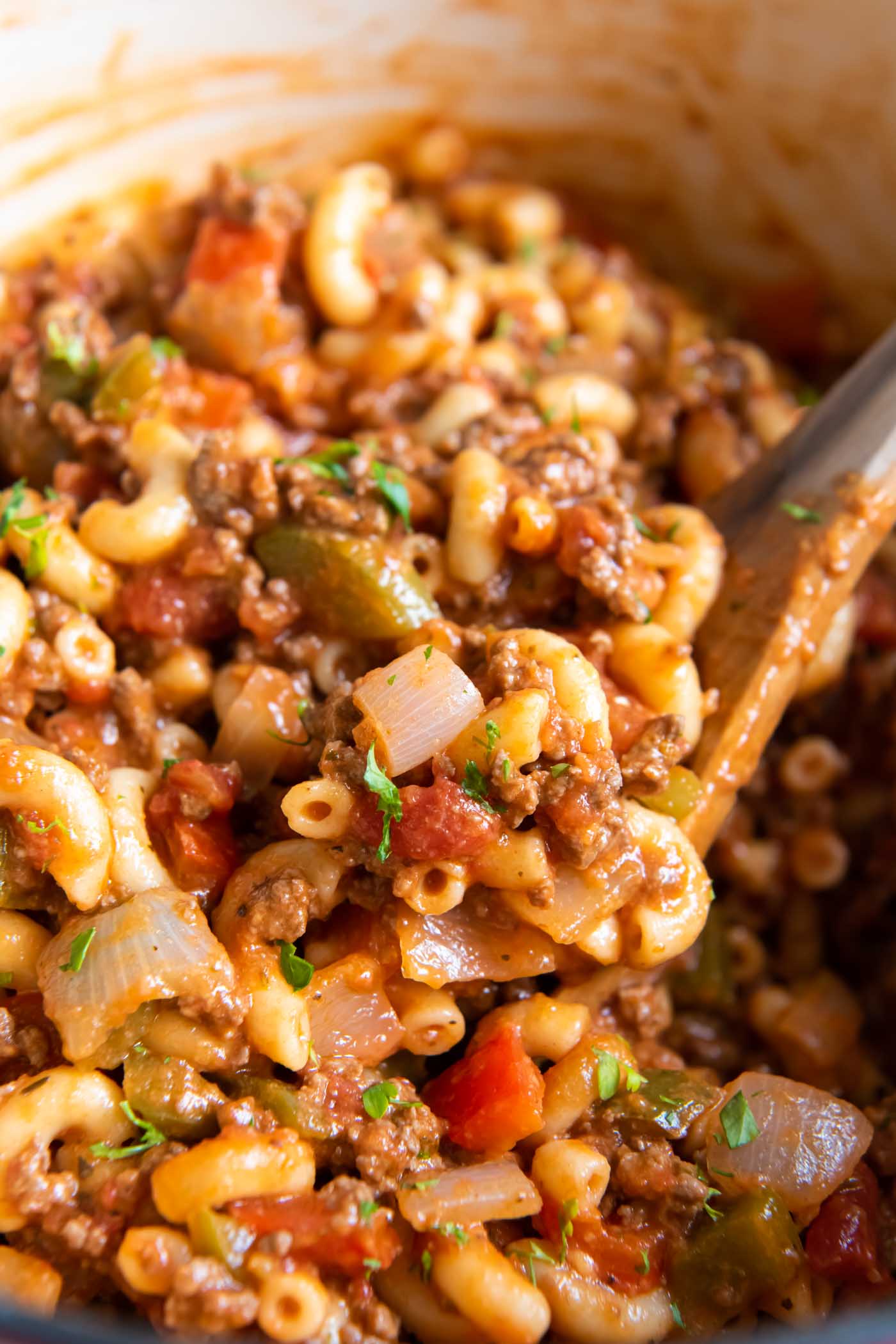 Close up of American goulash in a pot with a wooden spoon.