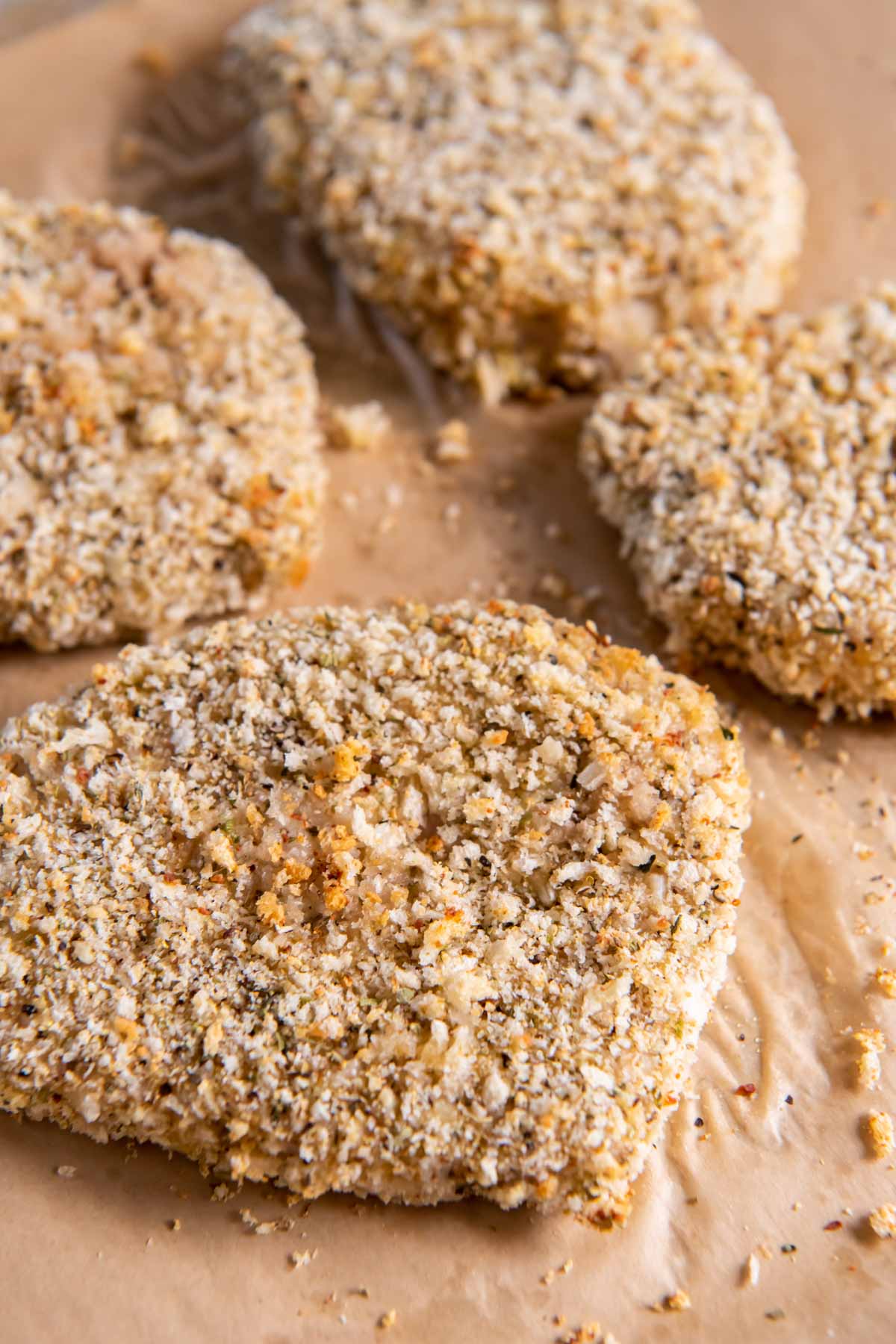 Baked breaded pork chops on parchment paper lined baking sheet.