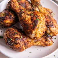 Close up of baked chicken legs on a plate.