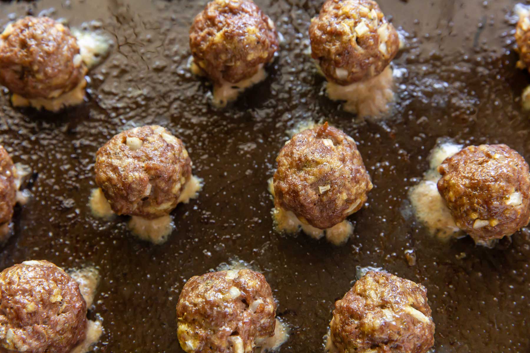 close up of baked meatballs on baking sheet