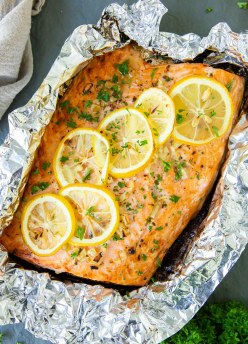 Baked salmon with lemon slices on top. in a piece of aluminum foil.