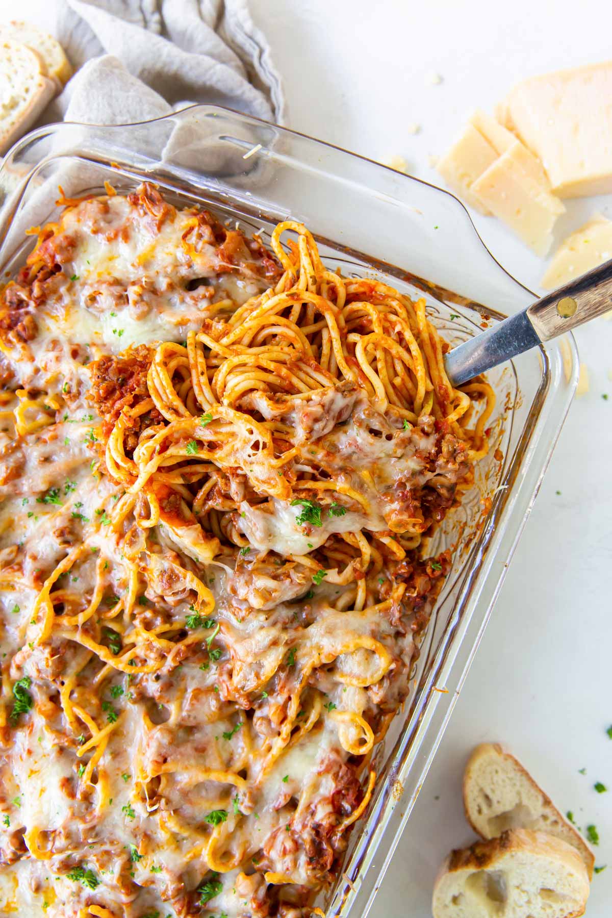 Baked spaghetti in baking dish with serving spoon.
