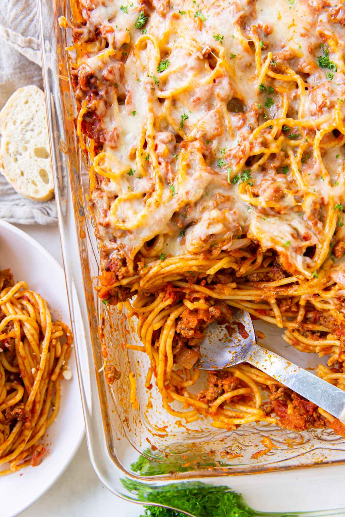 Baked spaghetti in casserole dish with serving spoon.