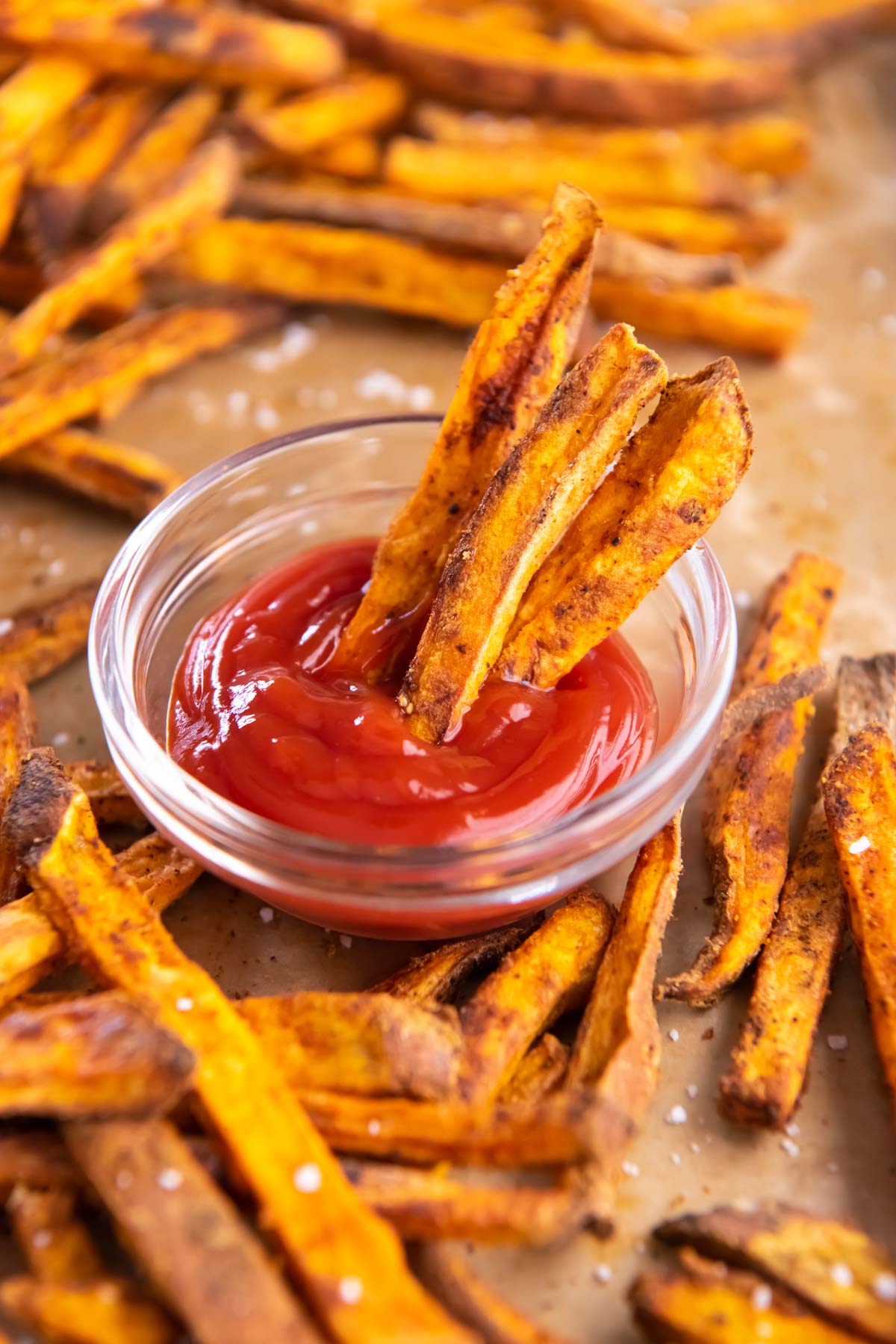 Three sweet potato fries dipped in small dish of ketchup.