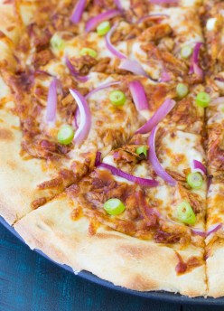 Close up of sliced bbq chicken pizza garnished with green onion.