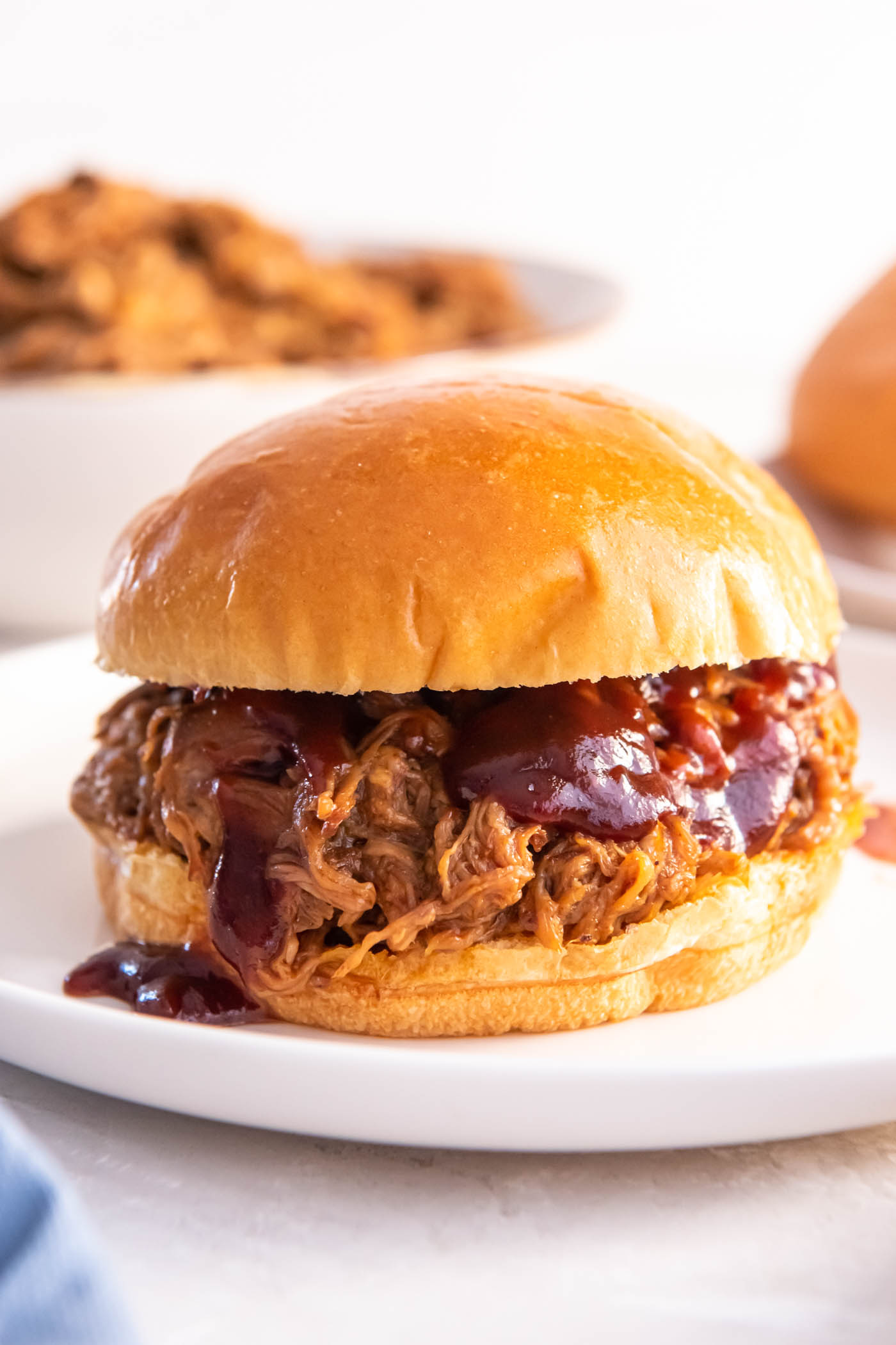 BBQ pulled pork sandwich served on a burger bun with extra bbq sauce.