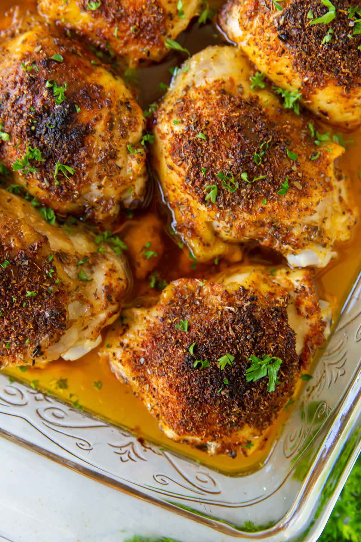 Close up of crispy bone in oven baked chicken thighs in baking dish.