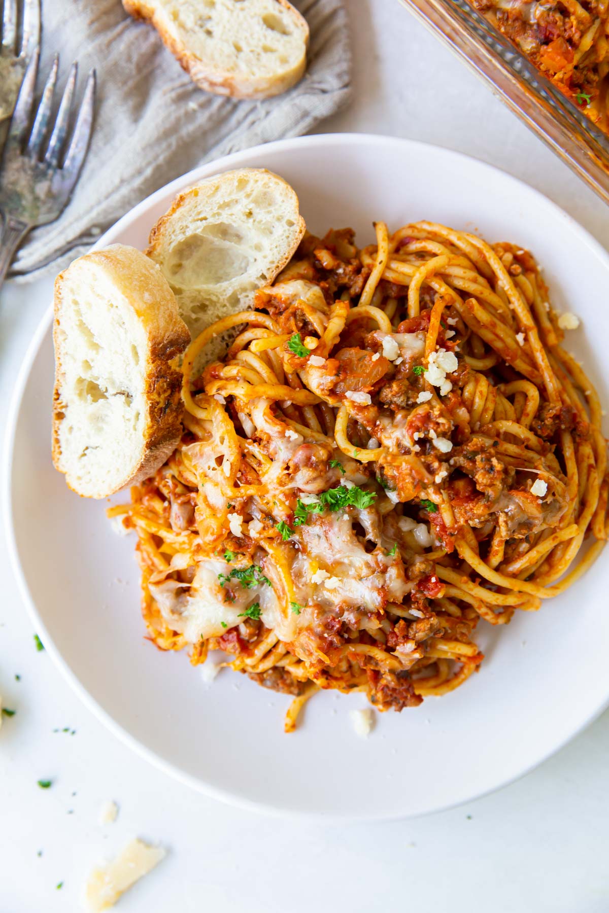 Serving of baked spaghetti on a plate with sliced bread.