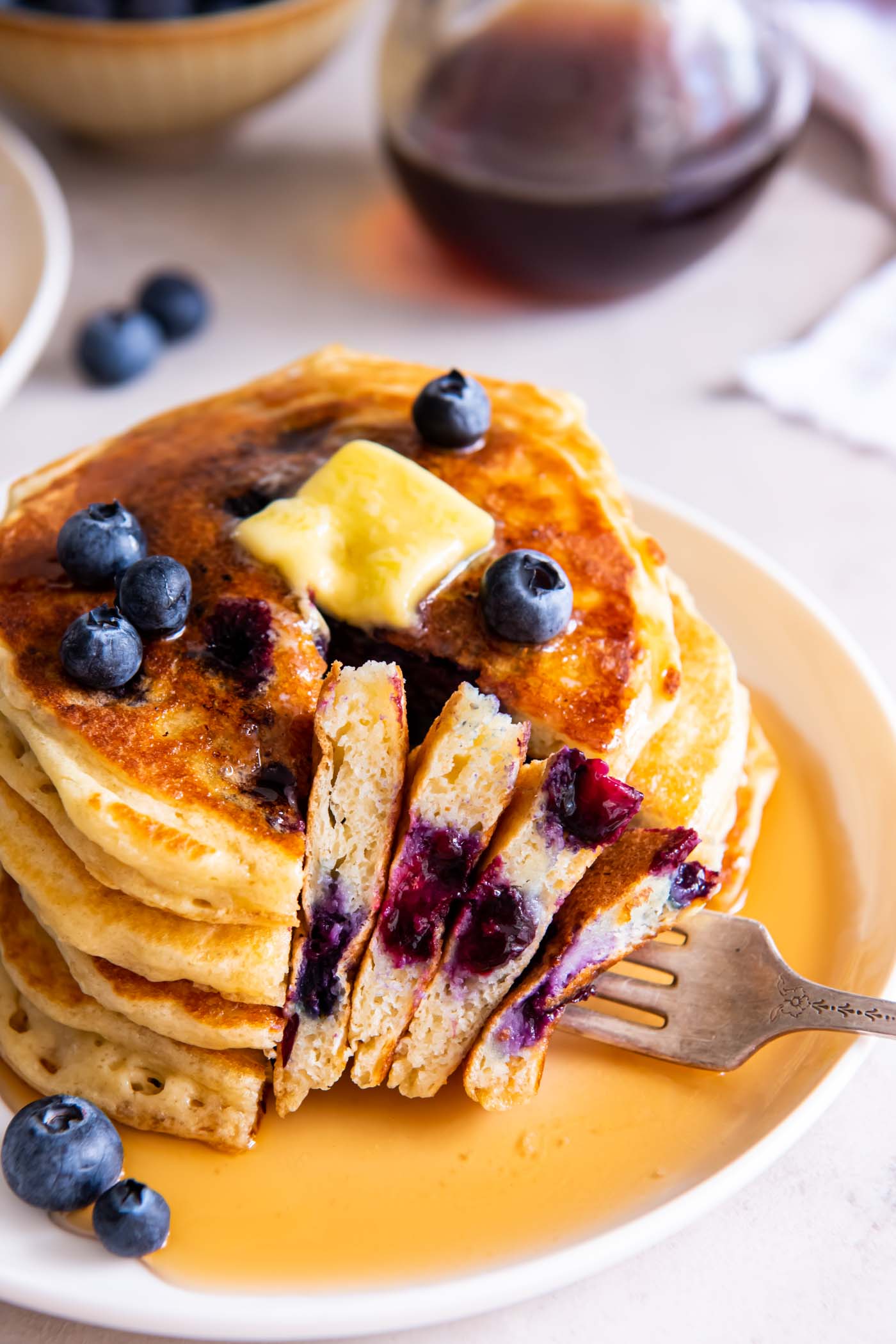Stack of blueberry pancakes with a bite on a fork.