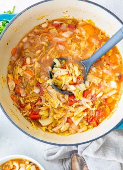 Cabbage soup in a dutch oven pot with a ladle.
