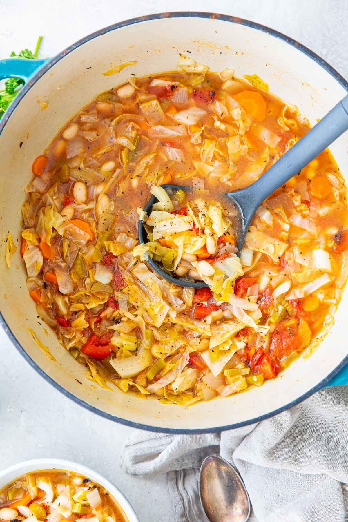 Cabbage soup in a dutch oven pot with a ladle.