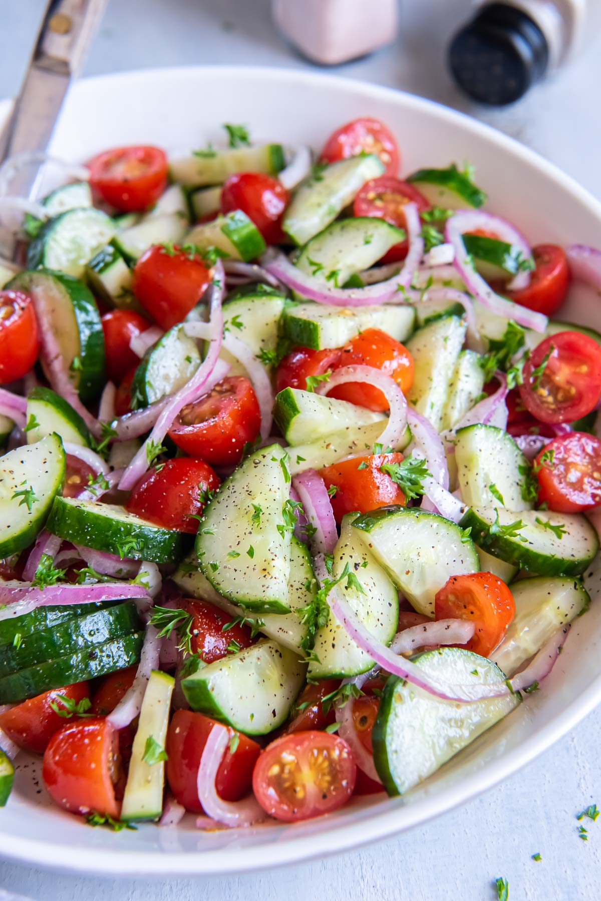 Close up of cucumber tomato salad in a white bowl.