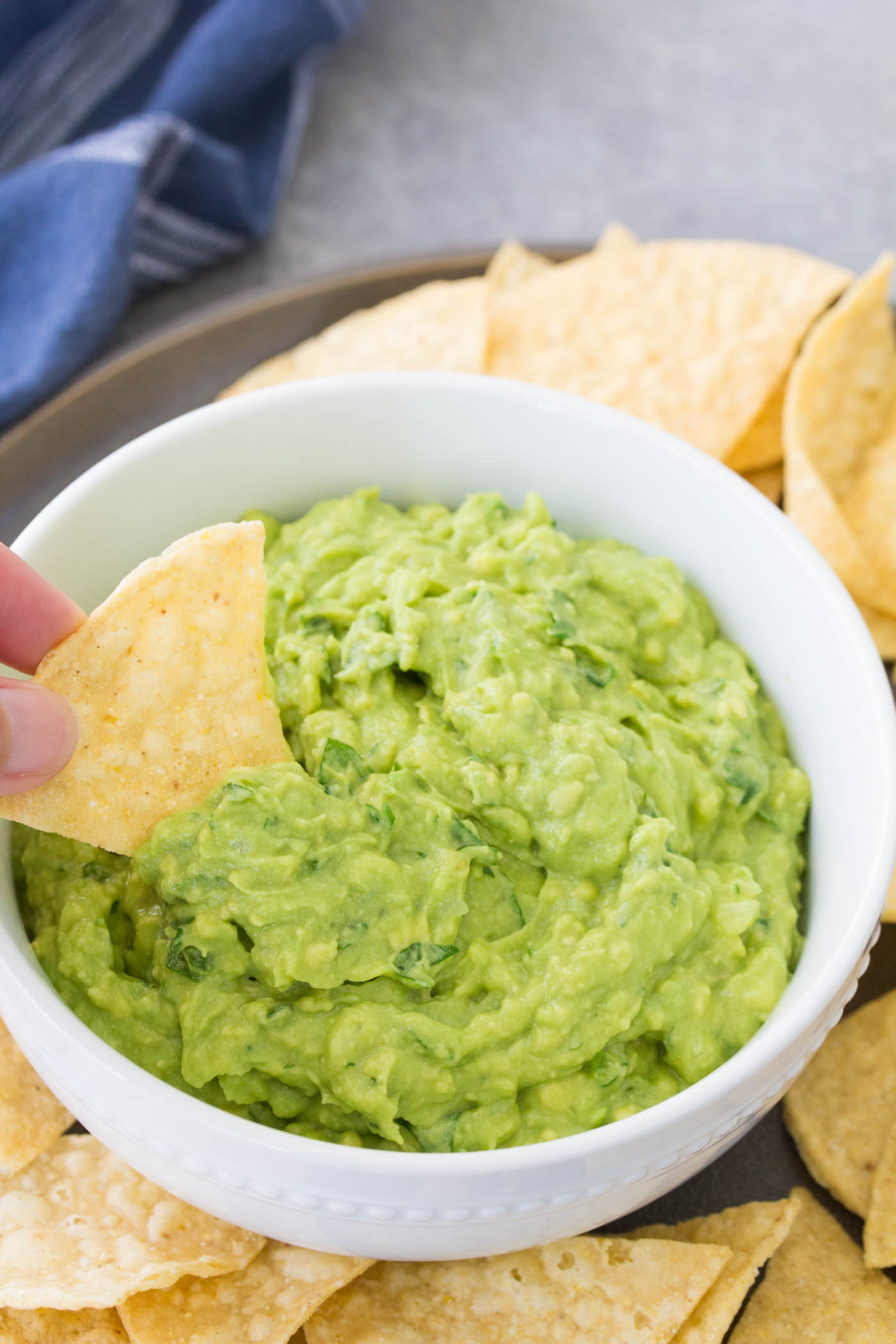 Scooping guacamole with a tortilla chip.