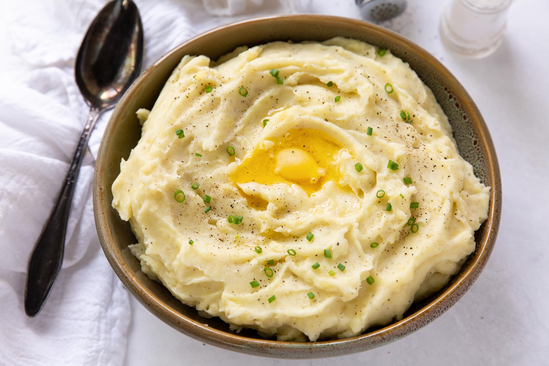 mashed potatoes with butter and chives in a serving bowl