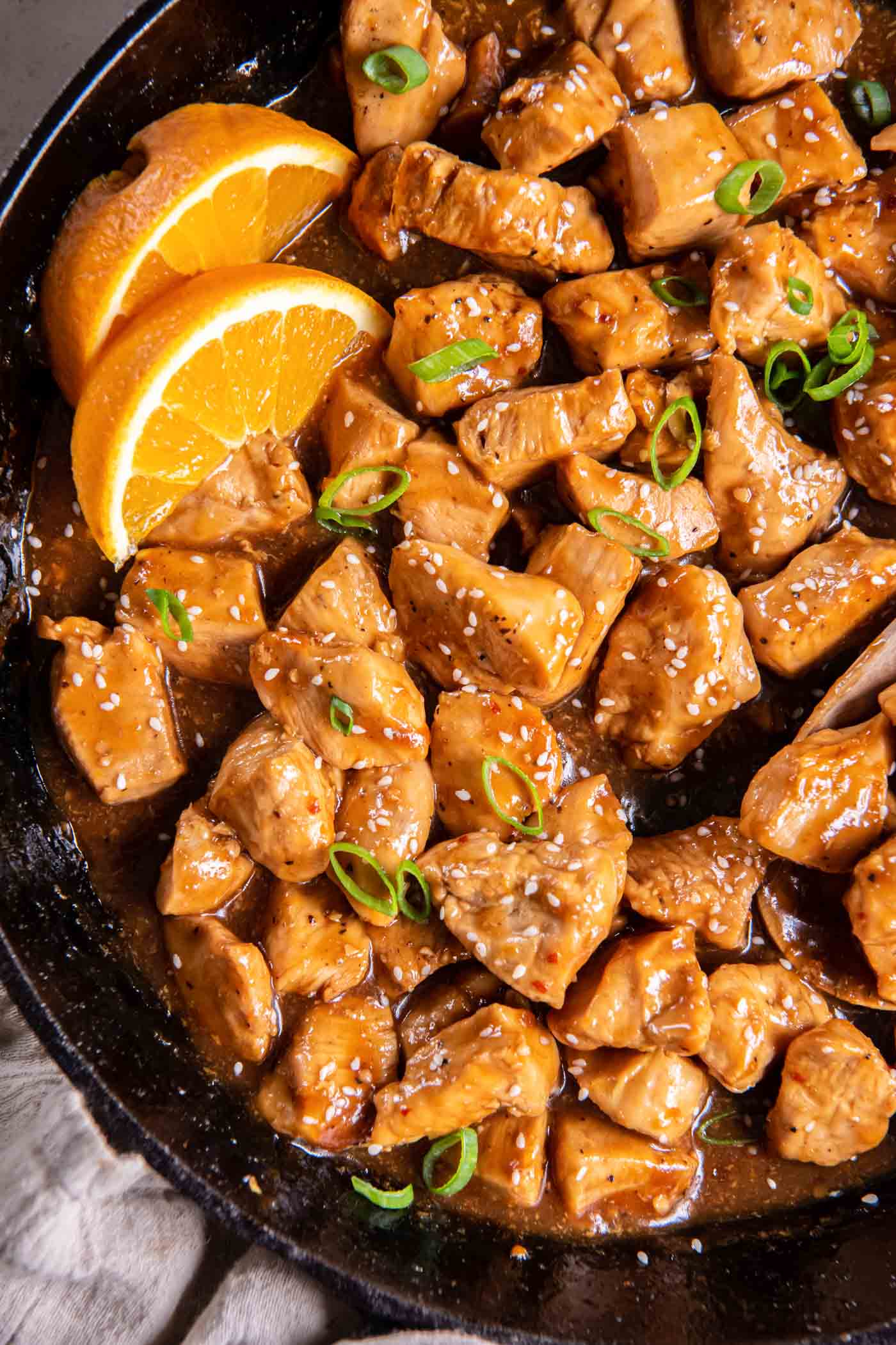 Orange chicken in skillet garnished with orange wedges.