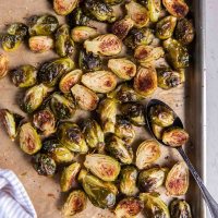 Roasted Brussels sprouts on baking sheet with a spoon.