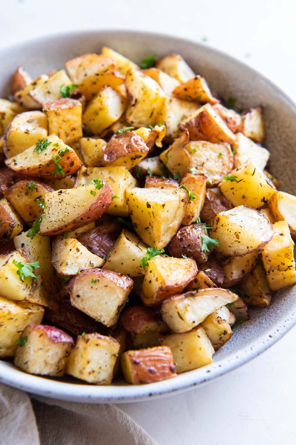 Roasted red potatoes in a serving bowl with parsley garnish.