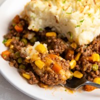 Close up of serving of shepherd's pie on a plate with bite on a fork.