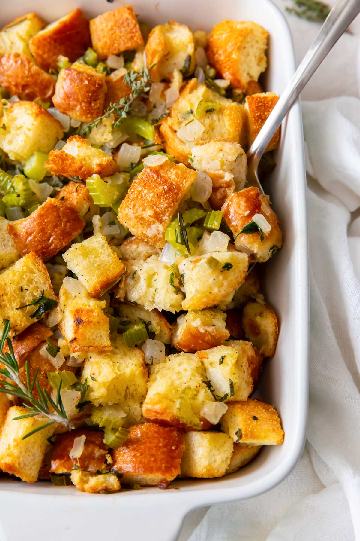 Thanksgiving stuffing in baking dish with serving spoon.