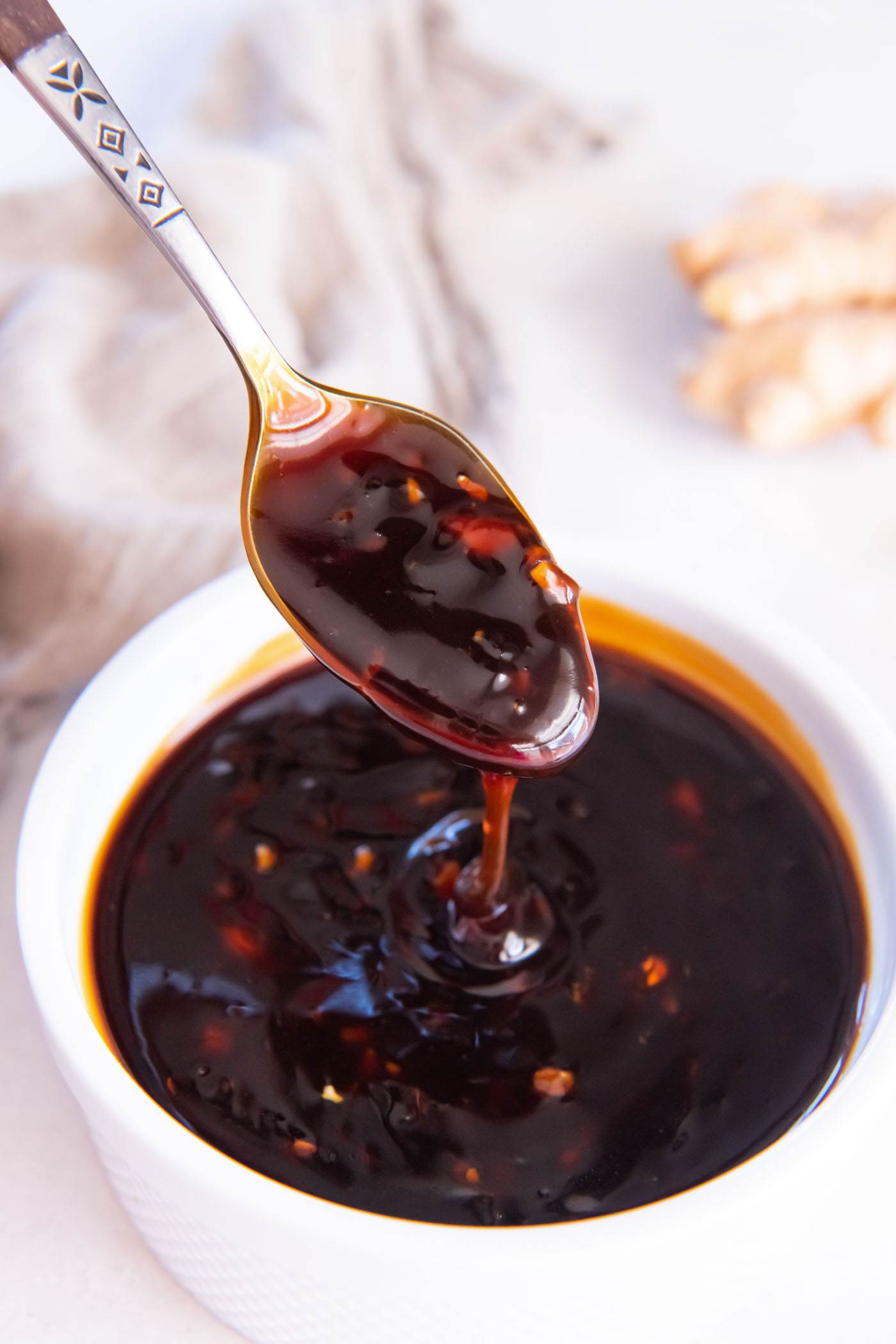 Teriyaki sauce dripping from spoon into bowl of sauce.