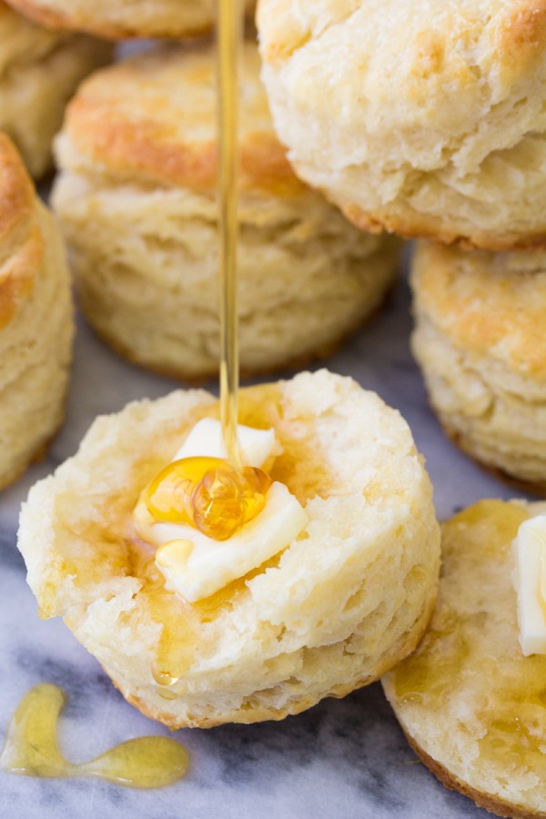 Drizzling honey on a biscuit with butter.