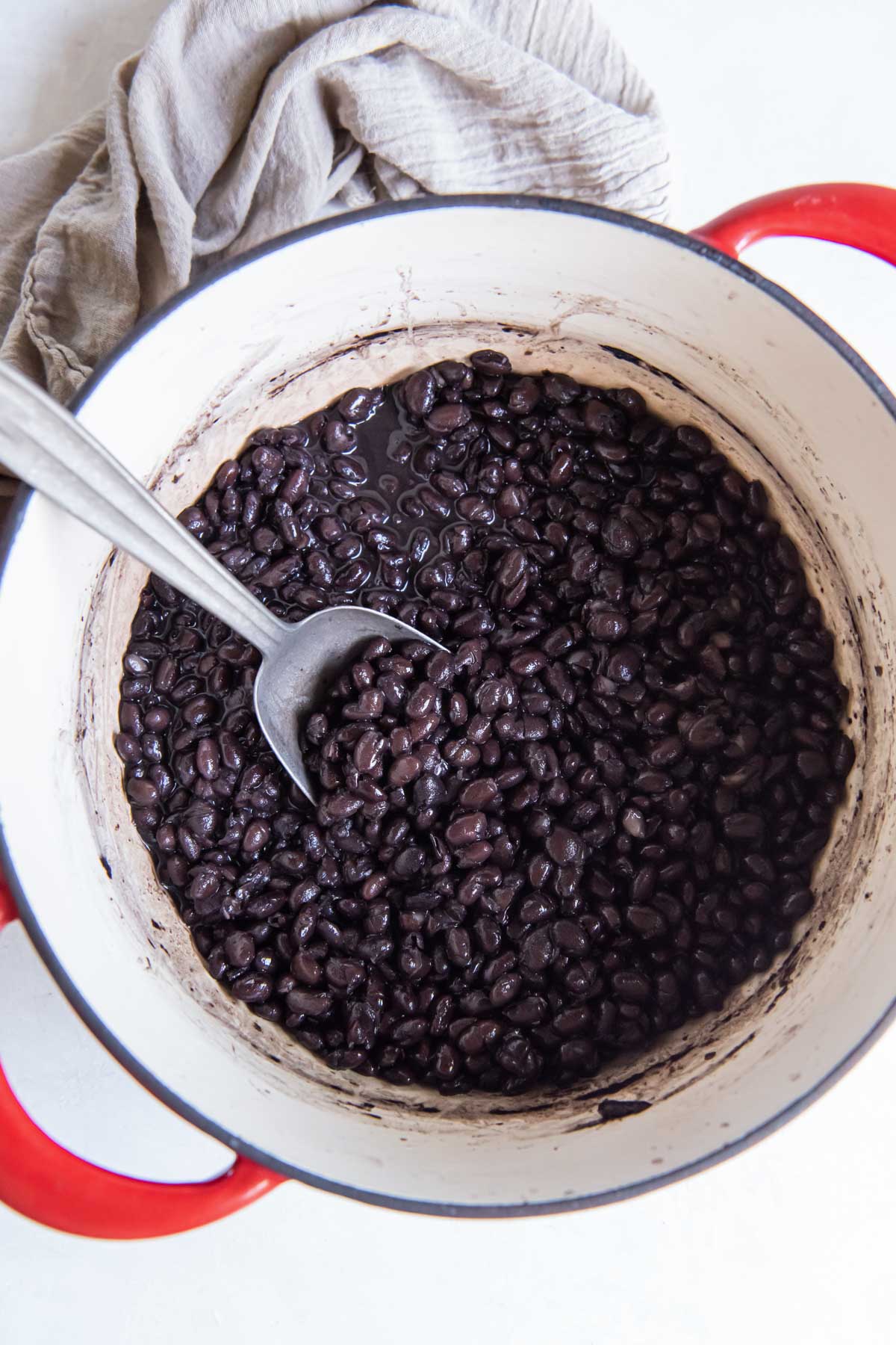 Cooked black beans from scratch in Dutch oven pot with serving spoon.
