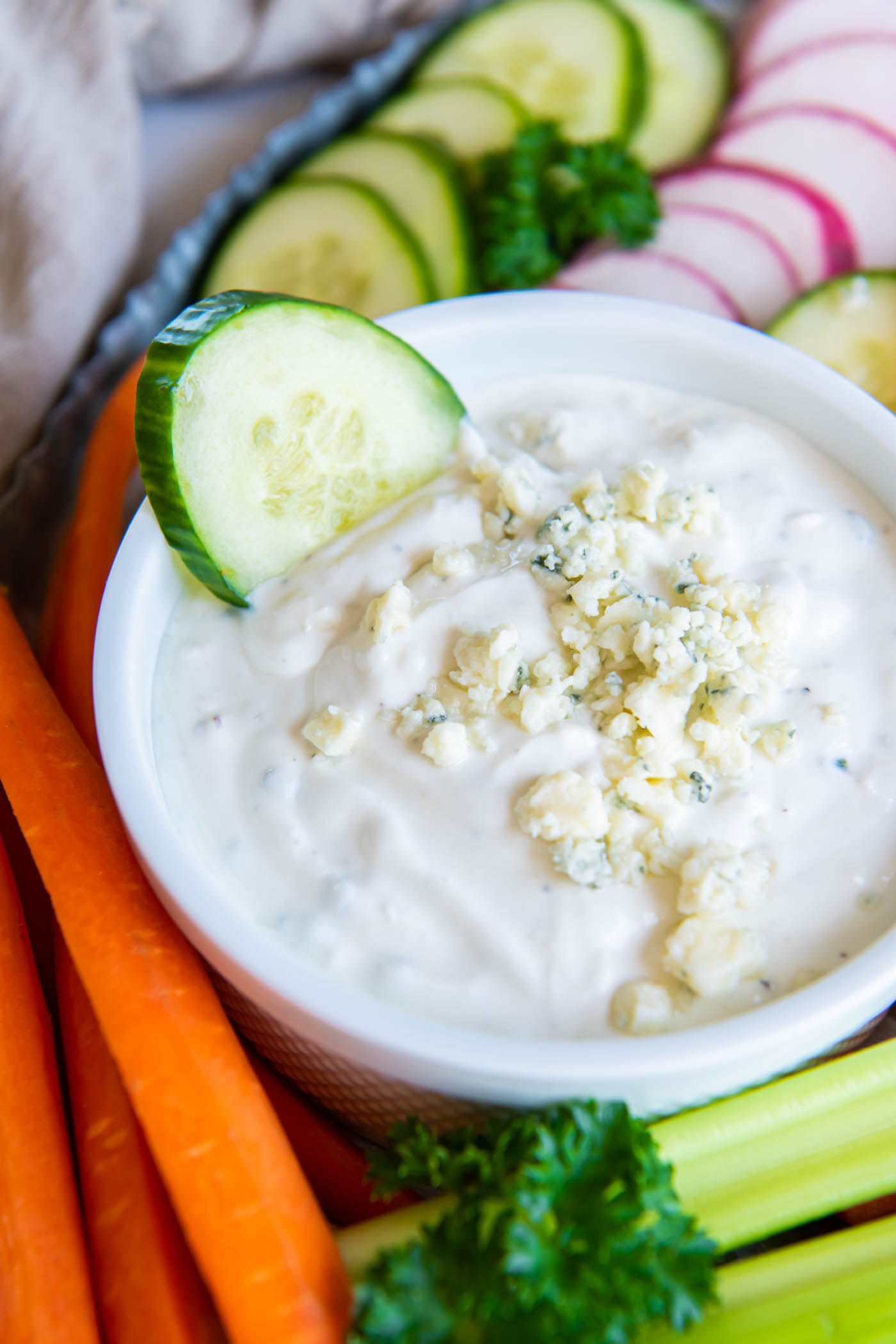 Blue cheese dressing in a small white bowl with a cucumber slice.