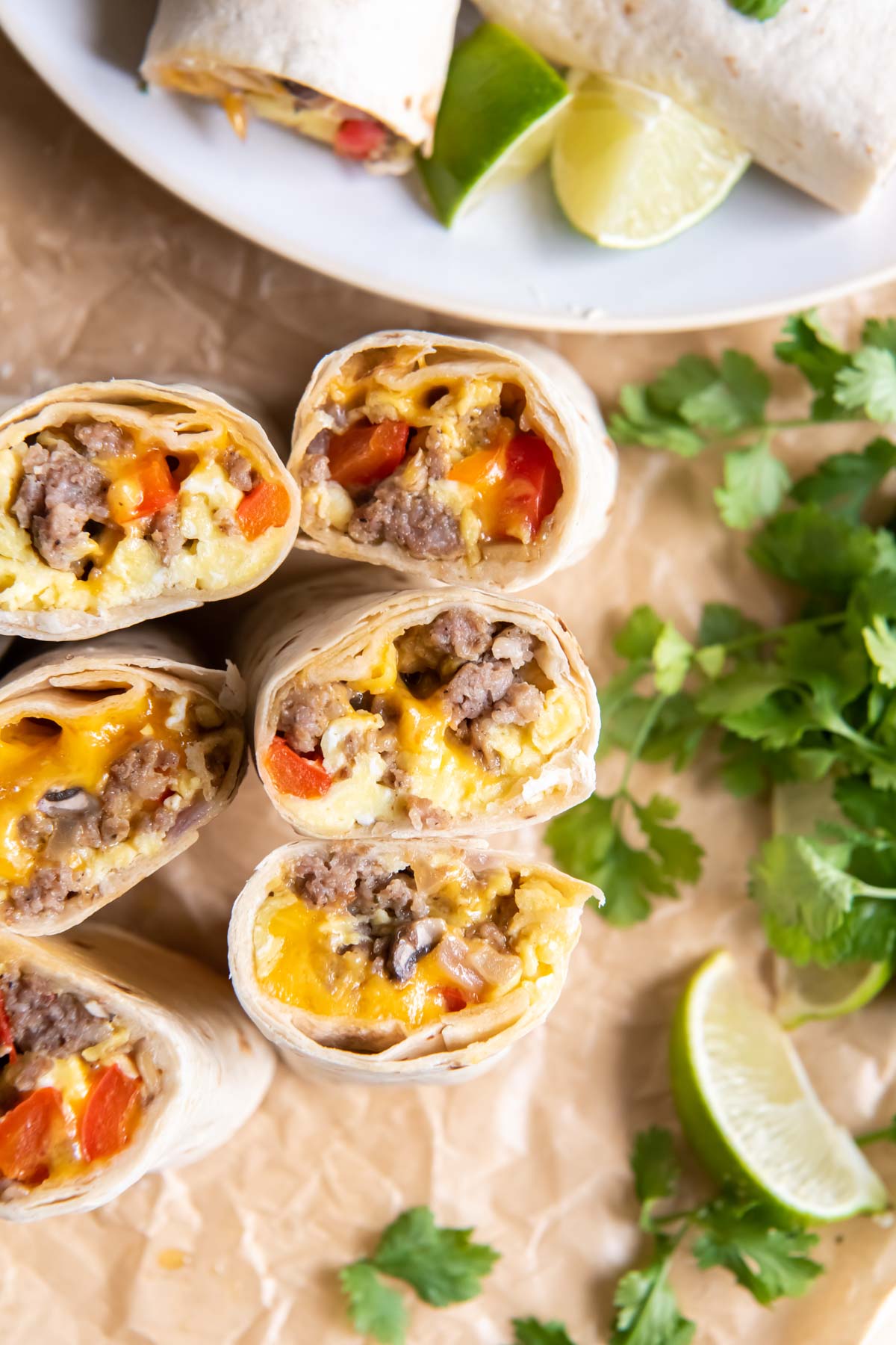 Breakfast burritos with sausage, eggs, veggies and cheese cut in half and standing up so you can see the filling.