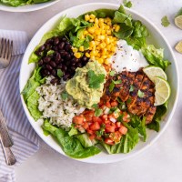Chicken burrito bowl with ingredients placed in different sections of the bowl.