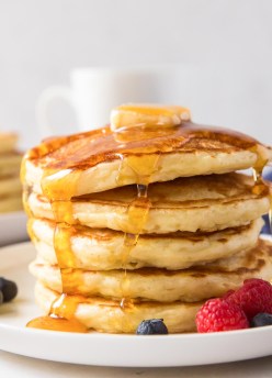 close up of stack of pancakes with butter and syrup