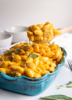 serving spoon filled with butternut squash mac and cheese held over dish