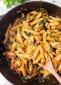 Cajun Chicken Pasta in a black pot with a wooden spoon.